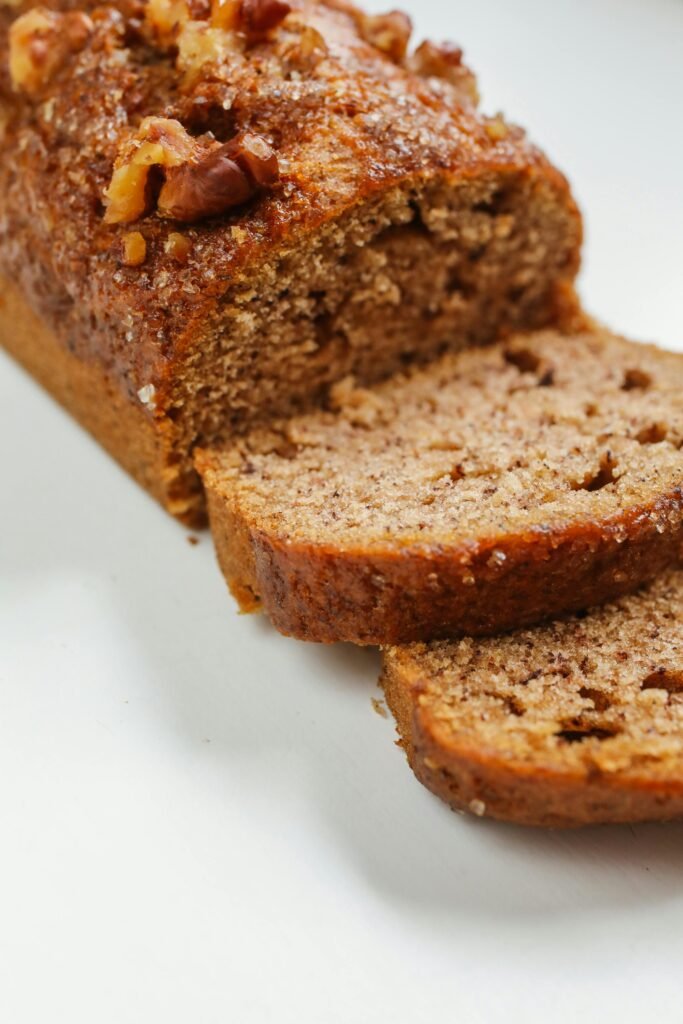 Close-up of sliced banana bread with walnuts on a white surface, perfect for breakfast.